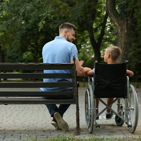 Dad At Park With Son In Wheel Chair